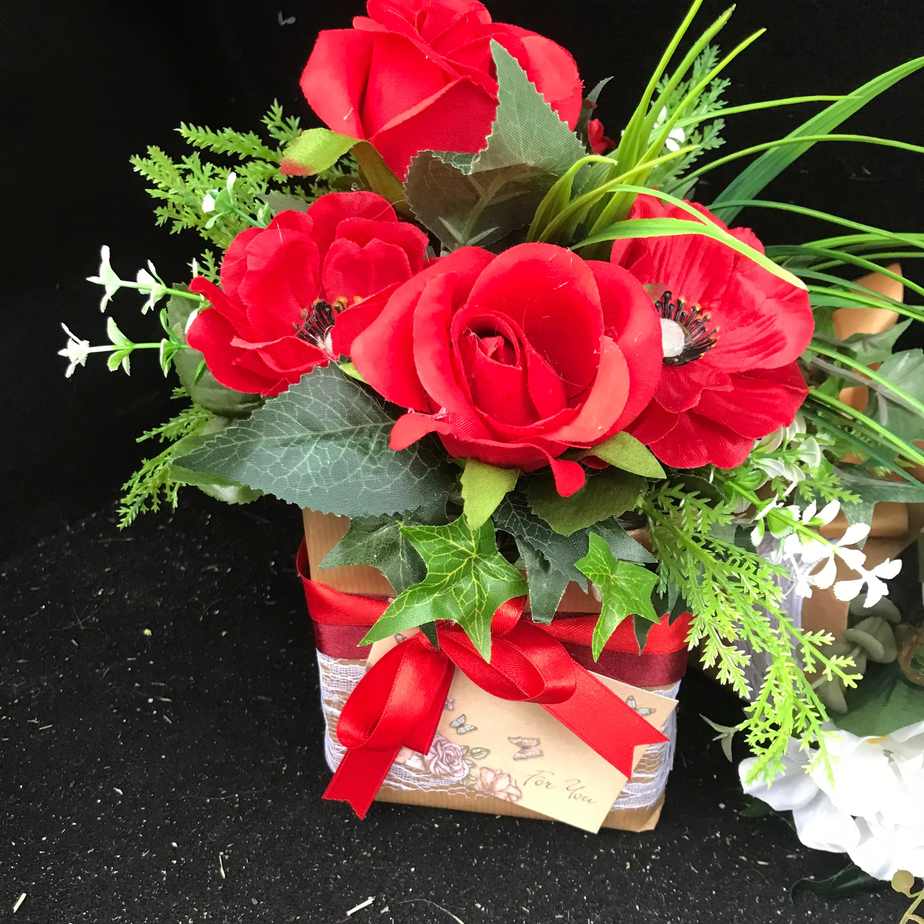 flower arrangement of artificial red anenomies & ivy in a gift bag